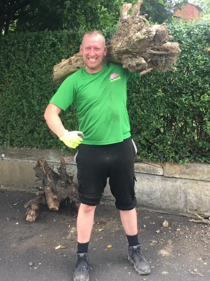 Dumpit crew member carrying a tree stump to the lorry